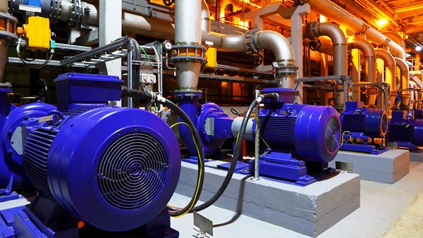 A row of motors and pumps in industrial environment