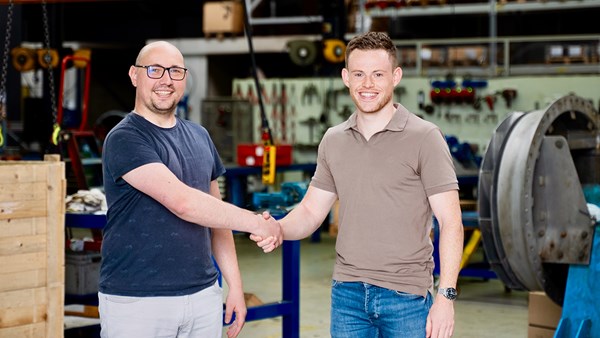 Two people shaking hands in a workshop environment