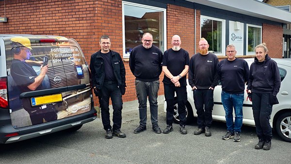 A group of people in workwear and a work vehicle in front of an office building