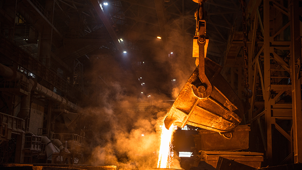 Ladle pouring liquid metal into molds at a steel mill.